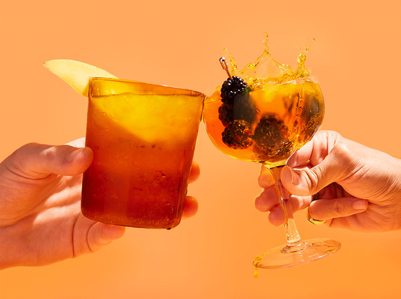 Two glasses of EnergyFizz clinking together with fruit garnishes