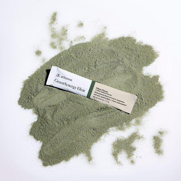 A GreenSynergy Elixir citrus flavour sachet resting on a pile of green powder